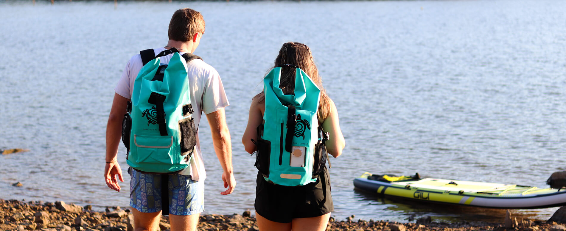 A man and a woman heading to a lake with a gili waterproof backpack