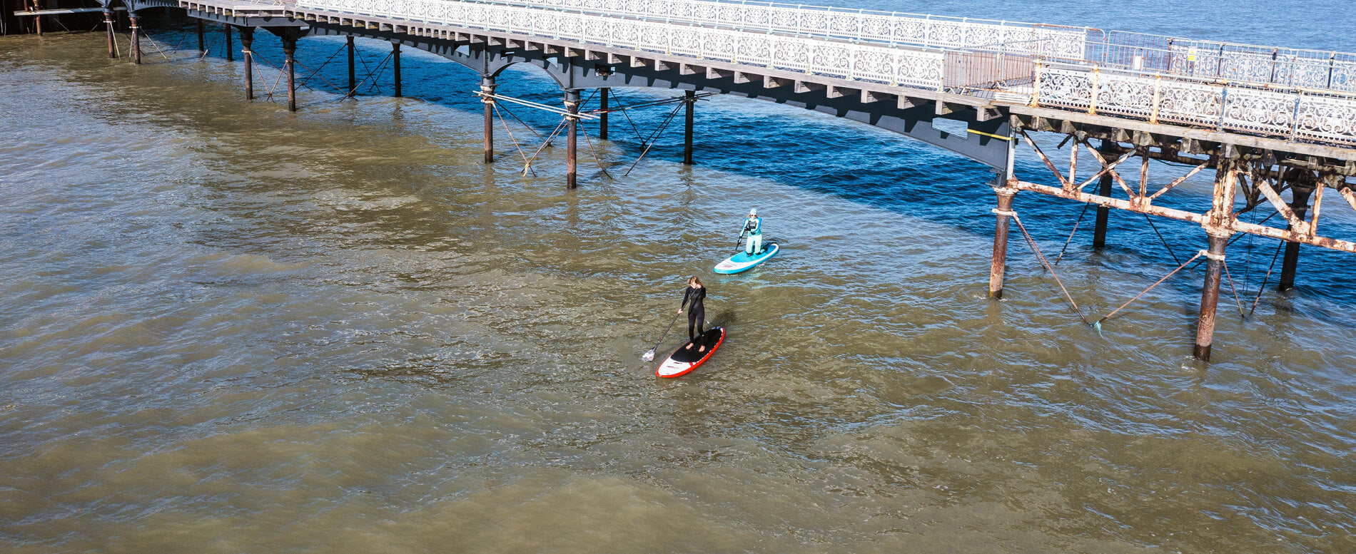 Two paddle boarders underneath Mumbles Pier